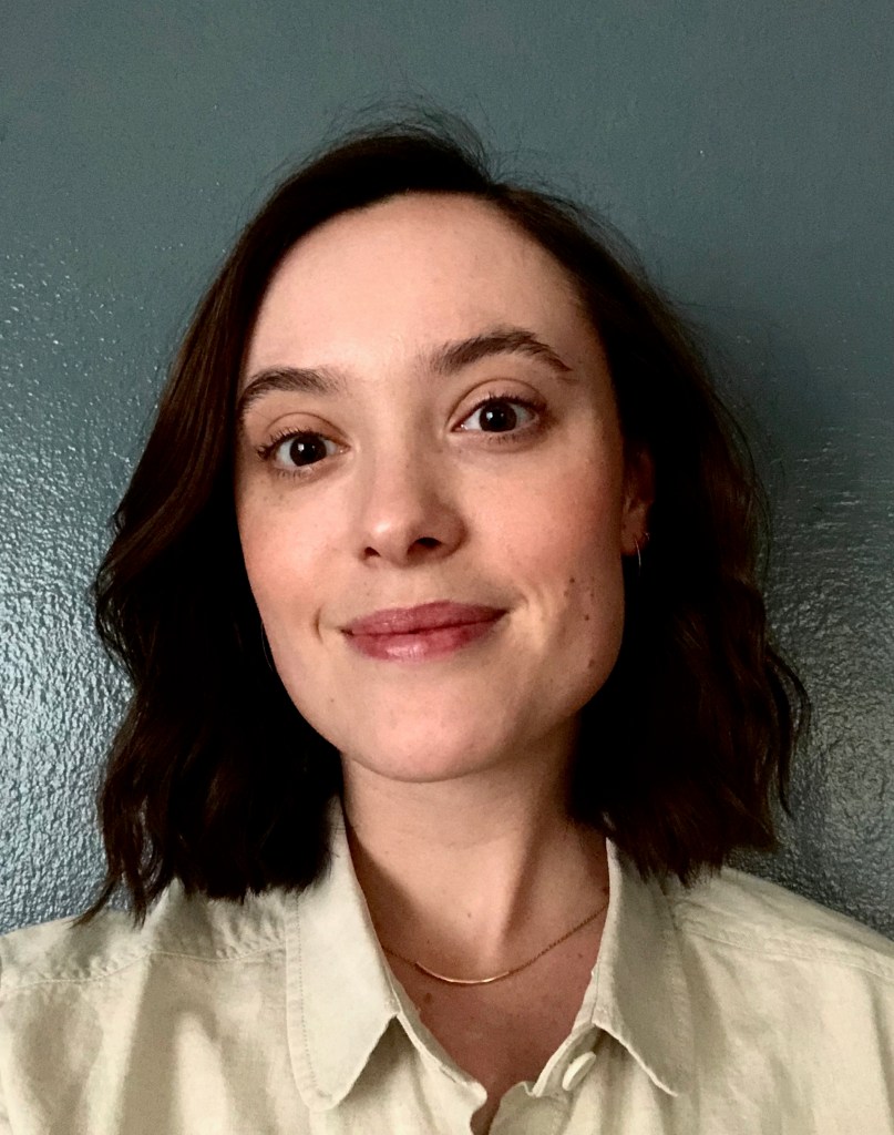 A headshot of Ellie, a young white woman with shoulder-length dark hair
