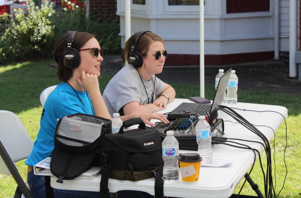 Ellie and her classmate sit at an audio table wearing headphones.